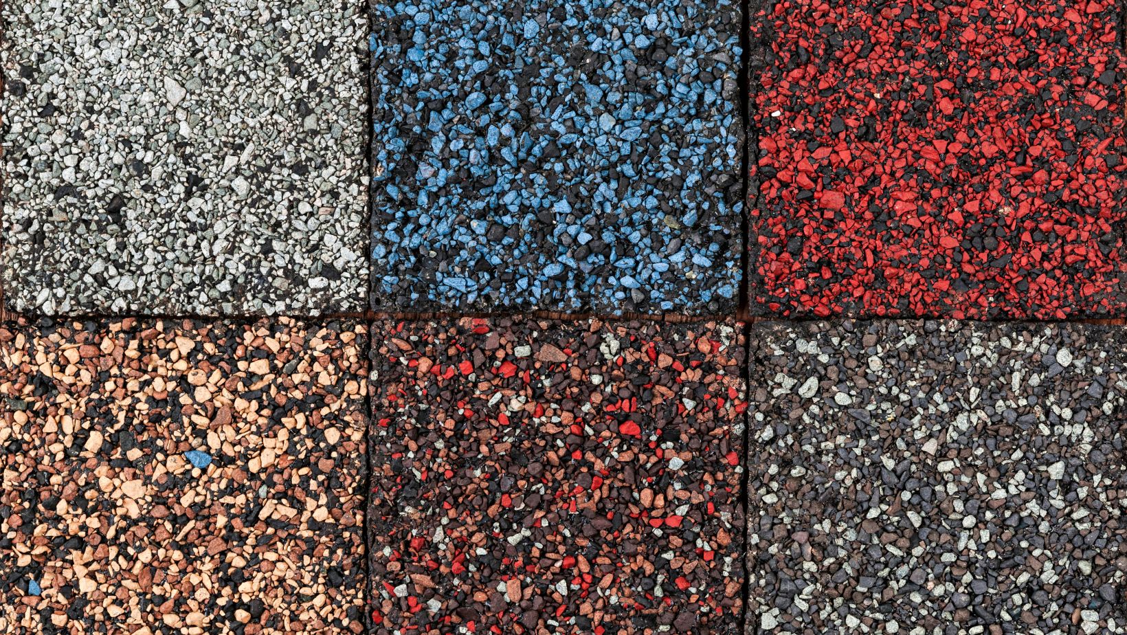 Close-up of various asphalt shingle samples in different colors and textures, showcasing durable and weather-resistant roofing options. Empire Contractors offers a wide selection of high-quality asphalt shingles for residential and commercial roofing projects.