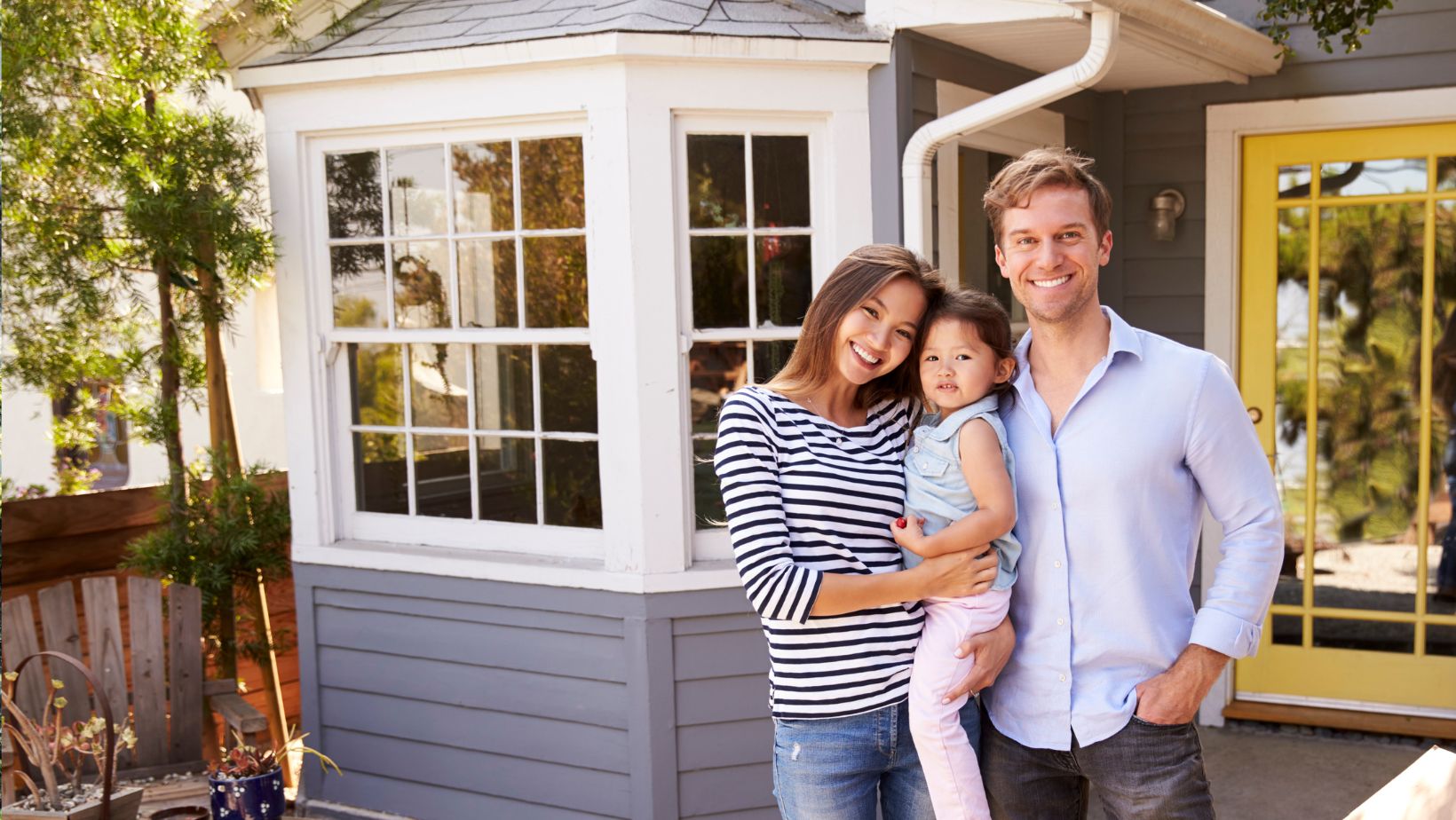 A happy family standing outside their beautiful home, showcasing a well-maintained roof and exterior. Empire Contractors LLC provides expert roofing, window, and gutter services in Cincinnati, OH, and surrounding areas to keep homes safe and looking their best.