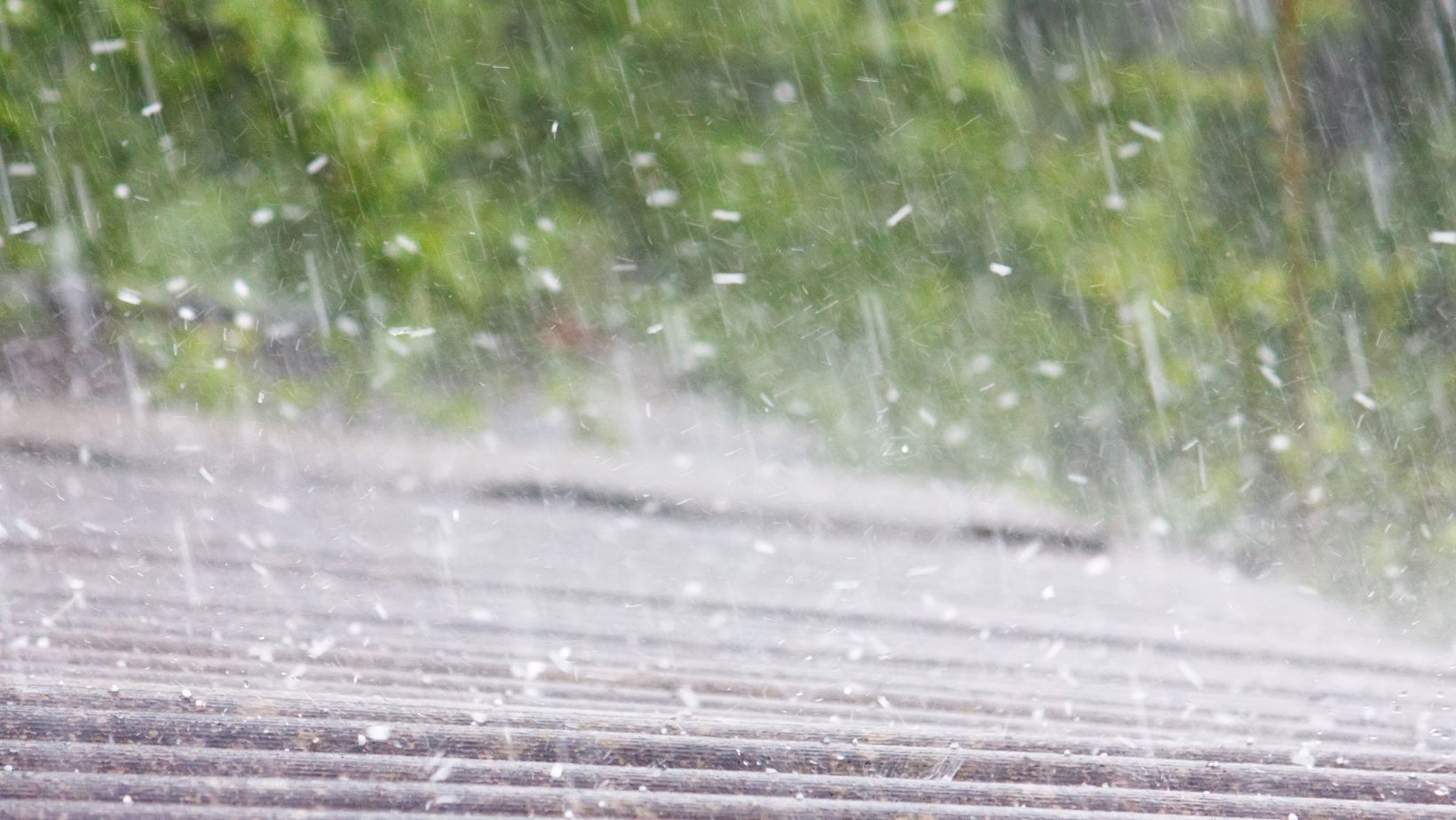 A residential roof being pelted by hail during a storm, highlighting potential damage risks such as dented shingles and leaks. Empire Contractors LLC provides expert hail damage roof repair and replacement services in Cincinnati, OH, and surrounding areas.