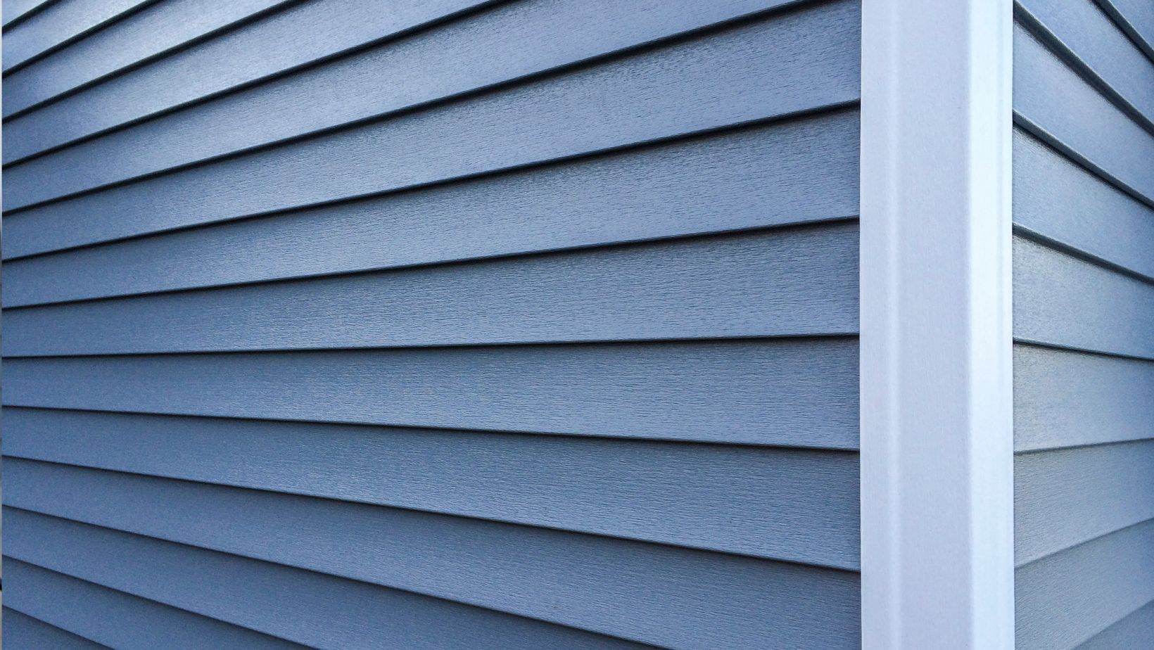 Close-up of modern blue vinyl siding on a home exterior, showcasing durable, weather-resistant construction. Empire Contractors specializes in professional siding installation for improved curb appeal and energy efficiency.