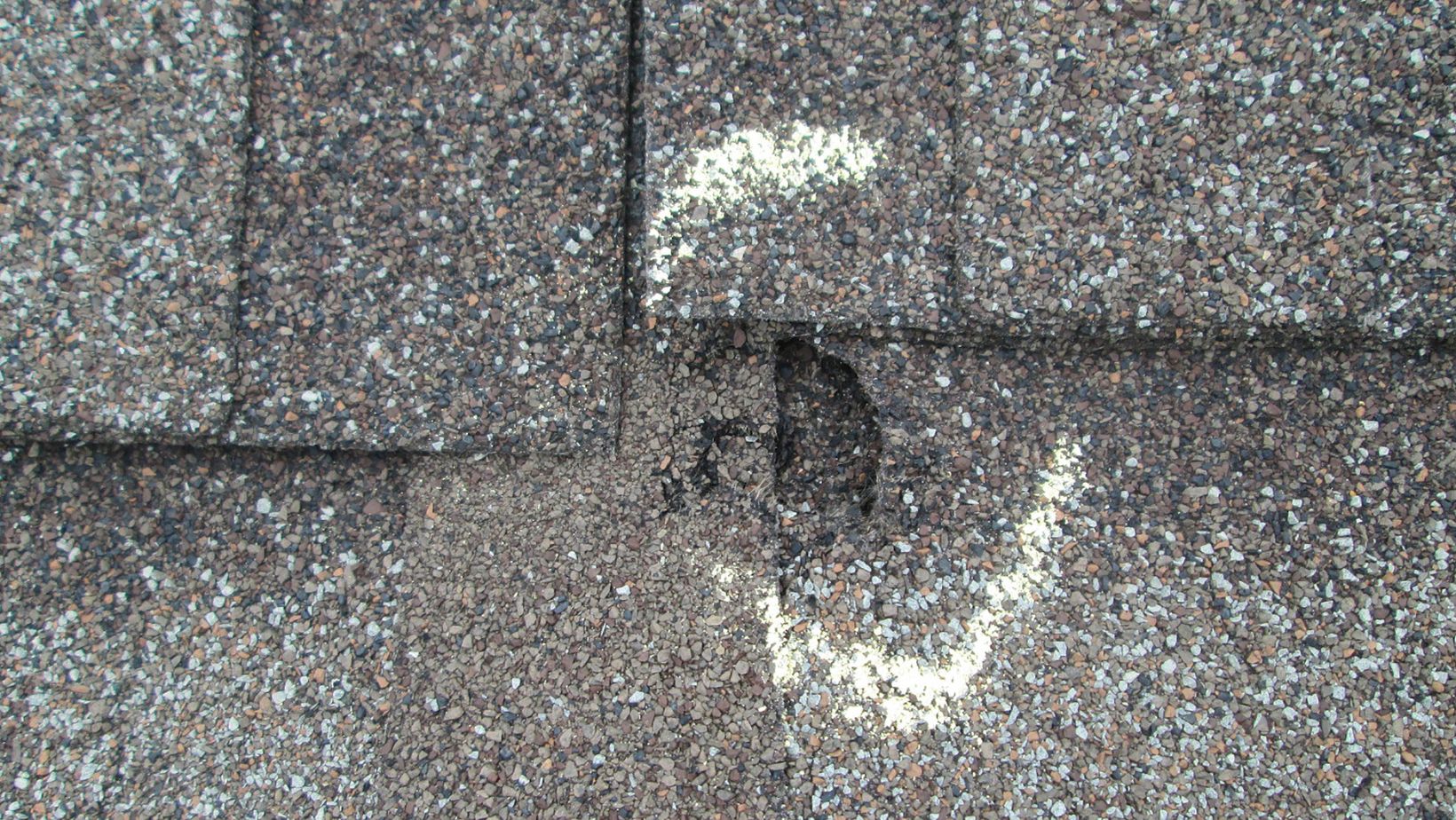 A residential roof with visible hail damage, including dented shingles and granule loss. Empire Contractors LLC provides expert hail-damaged roof repair and replacement services in Cincinnati, OH, and surrounding areas.