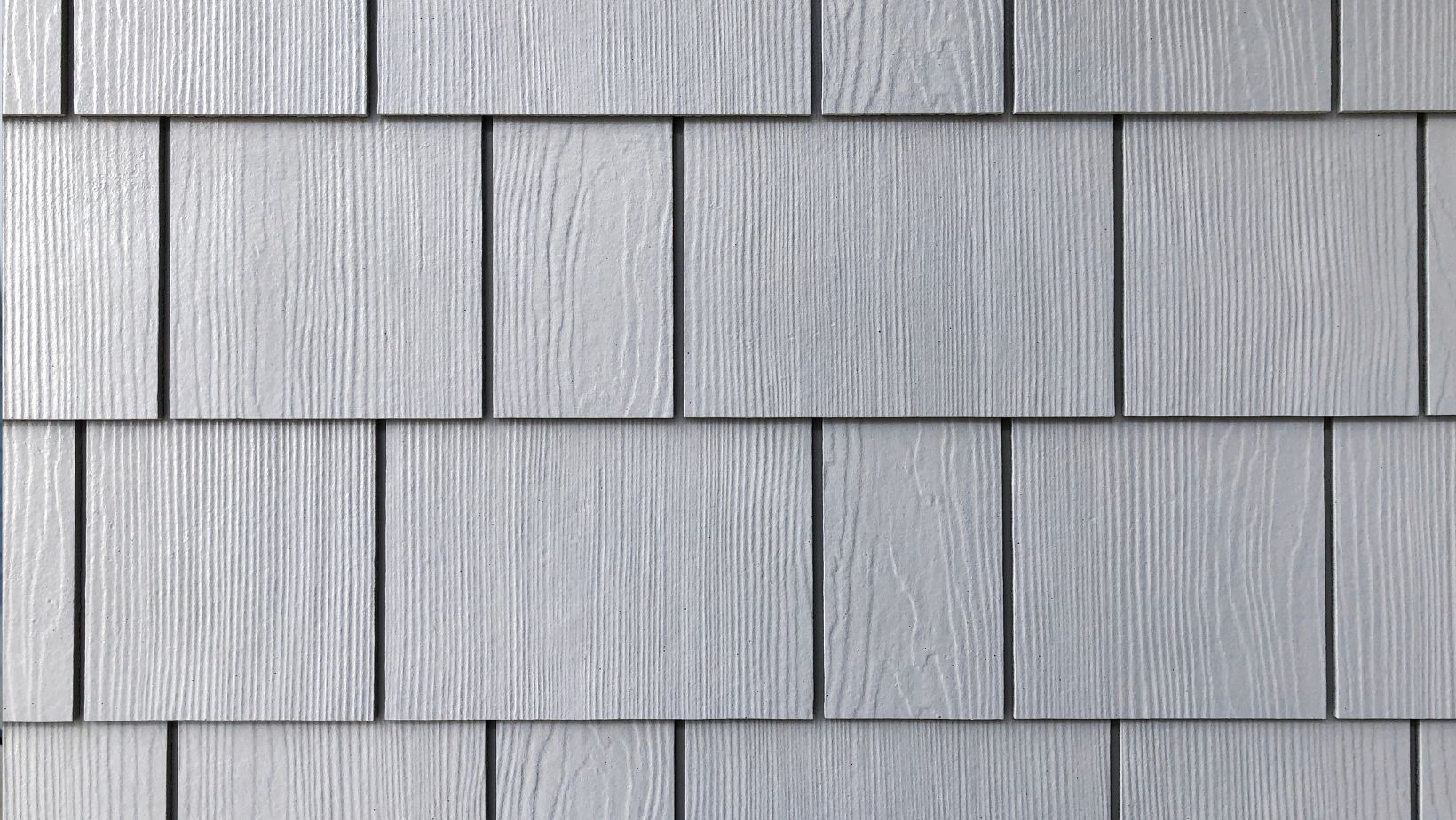 Close-up of gray shake and shingle siding with a wood grain texture, offering a classic and durable exterior finish. Ideal for adding character and weather resistance to homes. Empire Contractors specializes in professional shake and shingle siding installation for a timeless look.